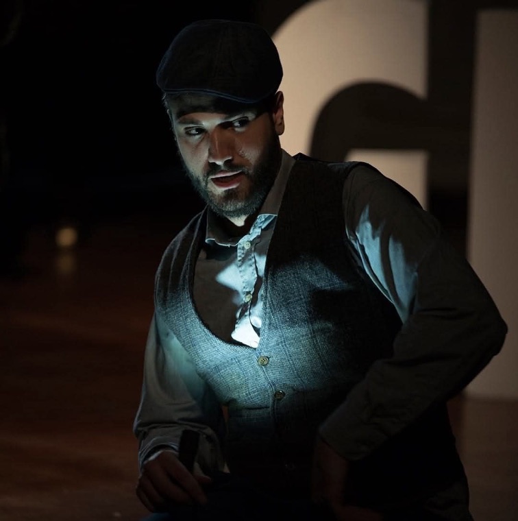 Luka Jozic in a flat cap and waistcoat, dramatic light